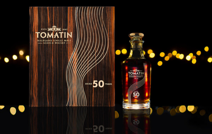 Branding photography for Tomatin whisky. The shot shows a bottle of whisky standing next to a special box with he words 50 years writing on it. In the background you can see out of focus lights. The mood is very dark and romantic. By Glasgow photographers Blink Imaging