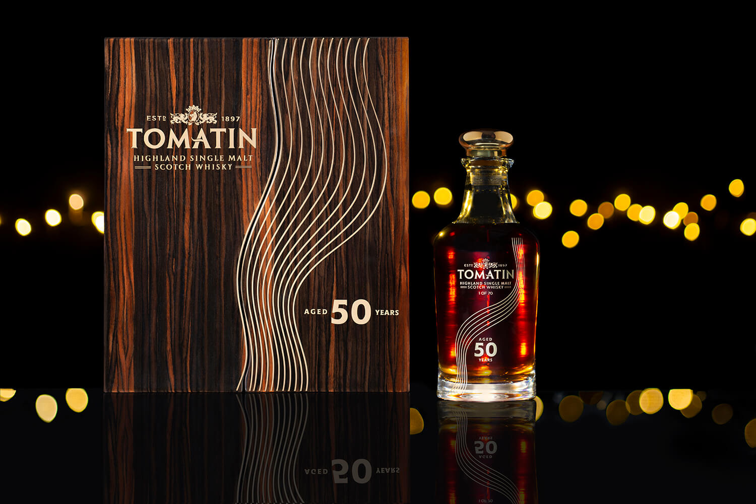 Branding photography for Tomatin whisky. The shot shows a bottle of whisky standing next to a special box with he words 50 years writing on it. In the background you can see out of focus lights. The mood is very dark and romantic. By Glasgow photographers Blink Imaging